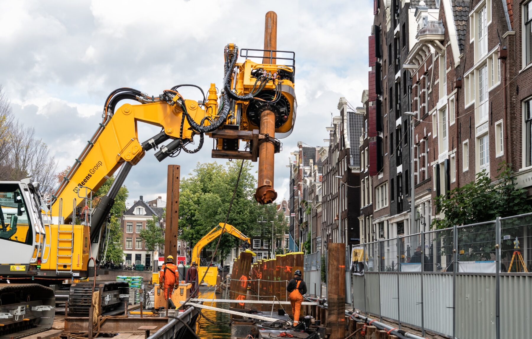 Machine plaatst een buispaal voor de bouw van een nieuwe kademuur aan de Herengracht.