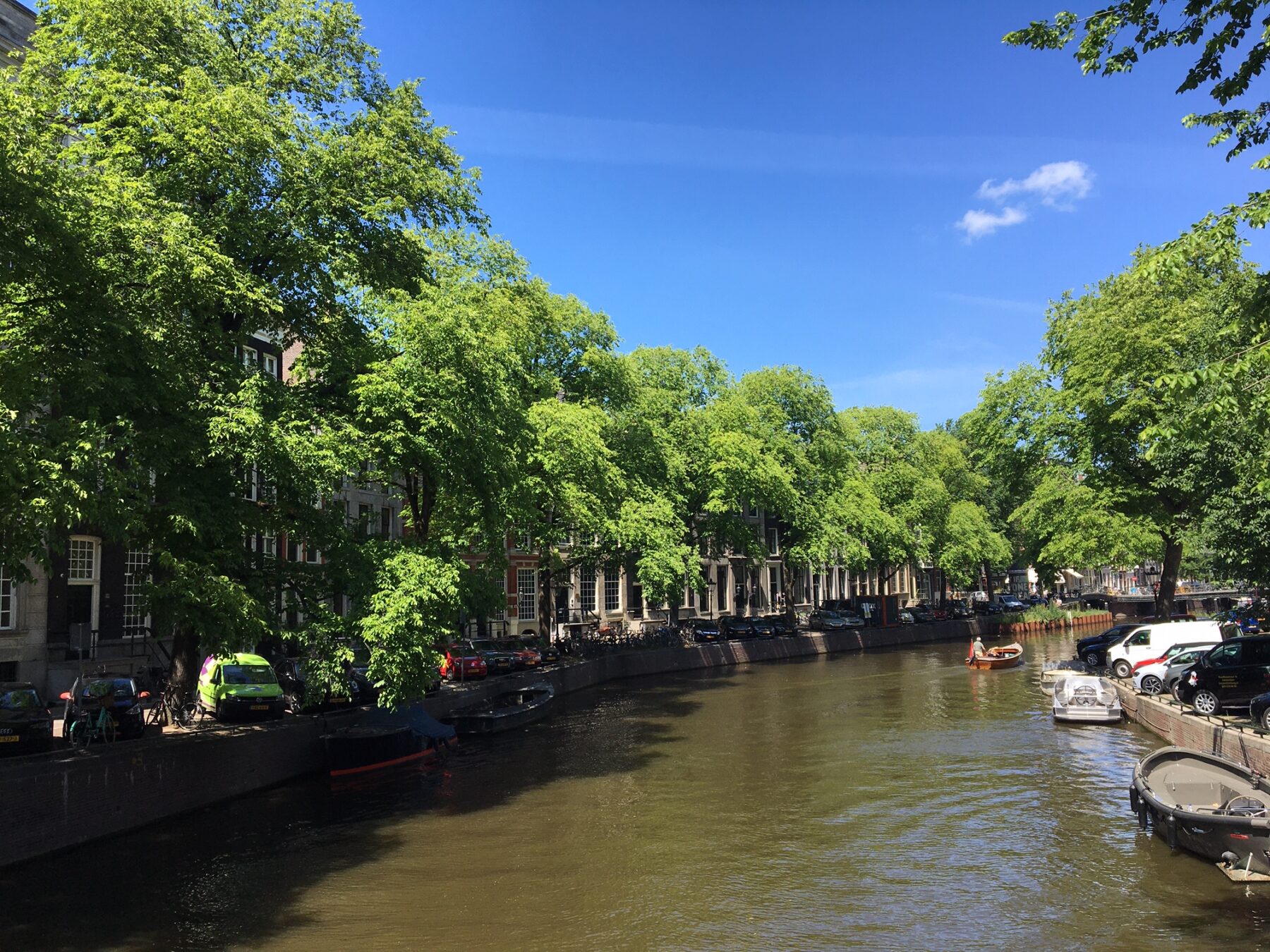 Bocht van de Herengracht met bomen vol in blad aan het water