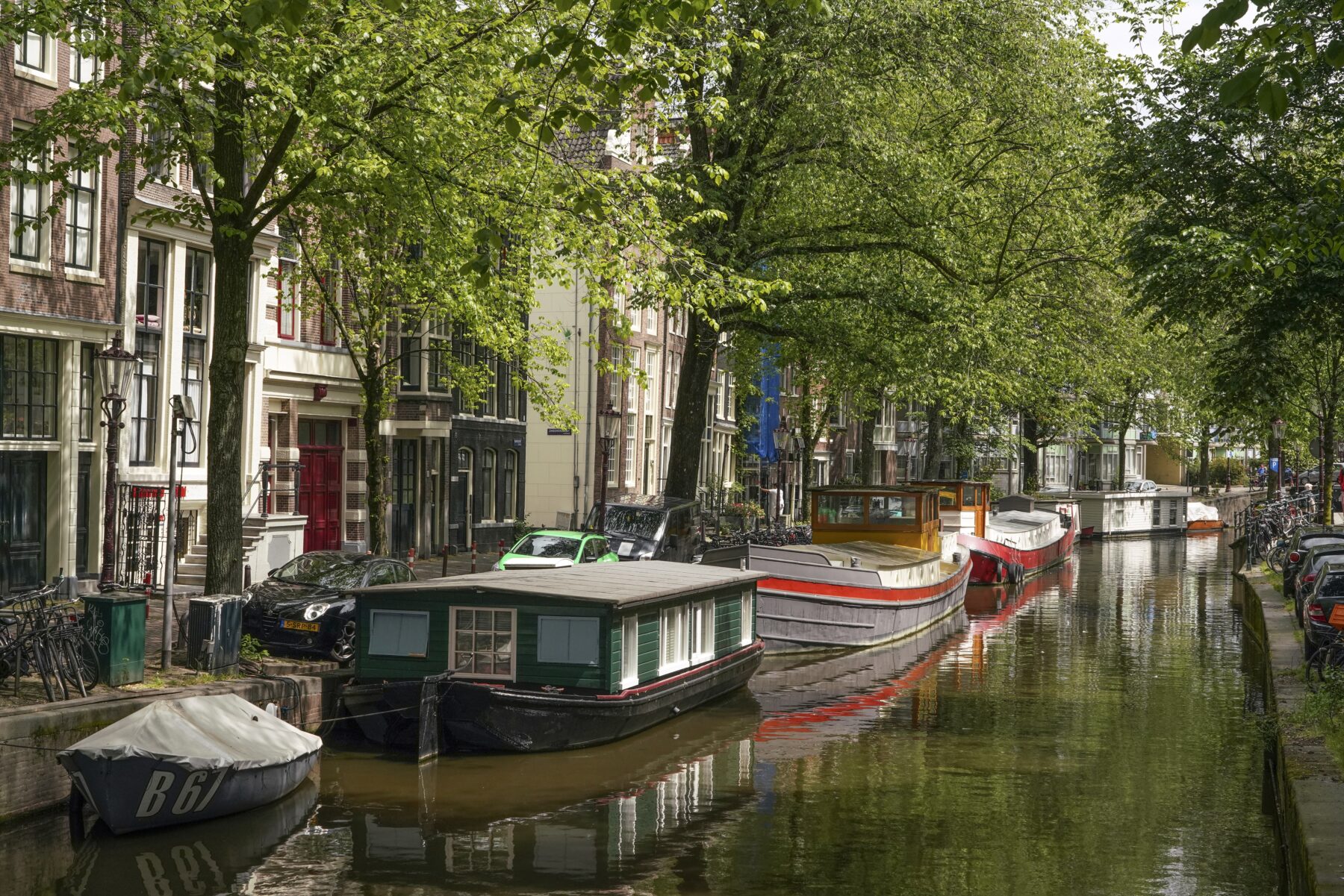 De Raamgracht met woonboten en bomen in blad aan de kade.